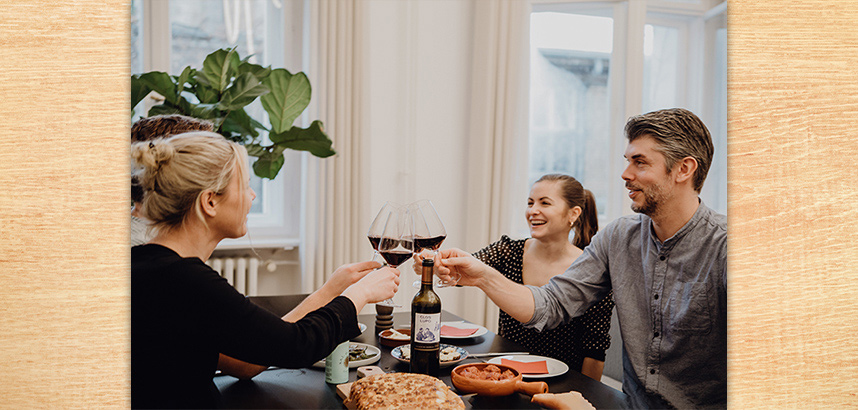 VINOS-Weinentdecker stossen beim Abendessen mit Weingläsern an.