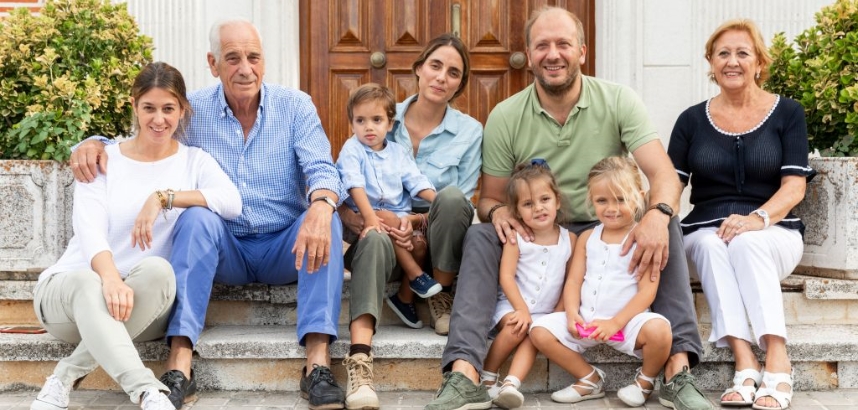 Eine Familie sitzt zusammen auf einer Steintreppe vor Haustür.