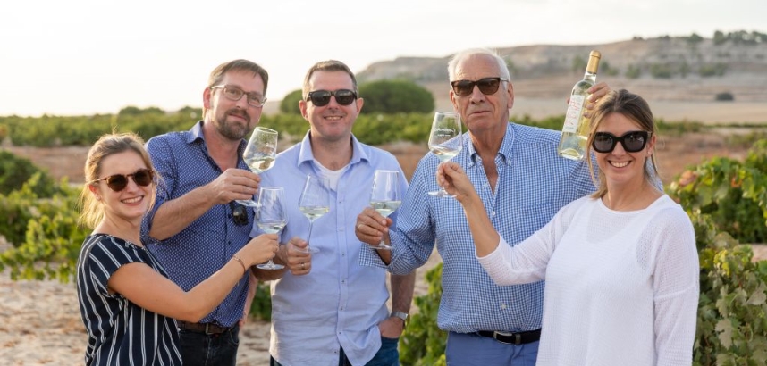 Gruppe von Menschen, die draussen Wein anstossen.